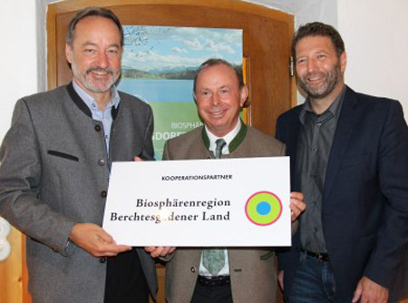 Drei in Trcht gekleidete Männer präsentieren stolz ein Schild mit der Aufschrift "Biosphärenregion Berchtesgadener Land"