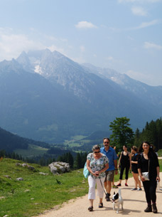Eine Gruppe Menschen wandert bei strahlendem Sonnenschein glücklich durch das Berchtesgadener Land
