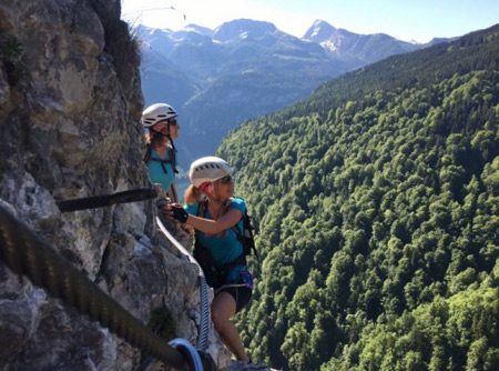Zwei Damen mit Helm und Sonnenbrille blicken während ihrer alpinen Wanderung in den Himmel