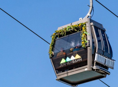 Eine Gondel der Jennerbahn befördert einige Gäste bei Sonnenschein auf den Gipfel