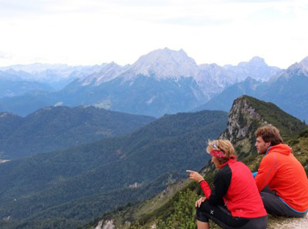 Zwei Wanderer sitzen auf de Gipfel eines Berges und blicken in das Lattengebirge