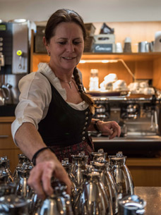Servicemitarbeiterin in Tracht im Natrurhotel Rehlegg in Berchtesgaden nimmt eine Kaffeekanne