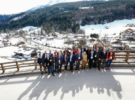 Eine Menschenmenge posiert vor verschneitem Bergpanorama für ein Foto